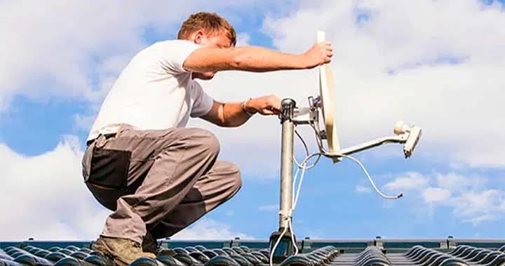 Installateur SOS-Télé posant une antenne satellite sur un toit